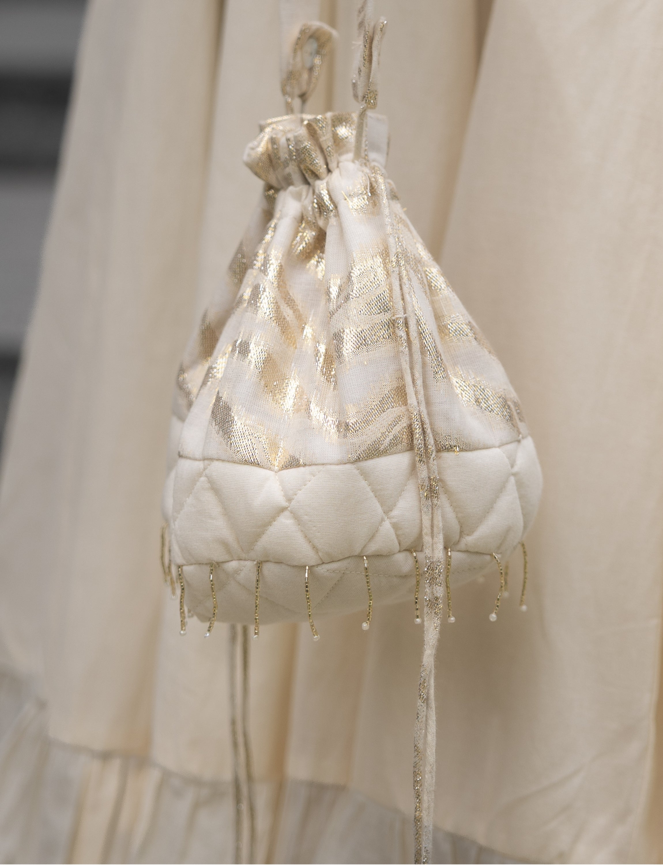 Off-White Quilted Potli with Gold Stripes and Tassels